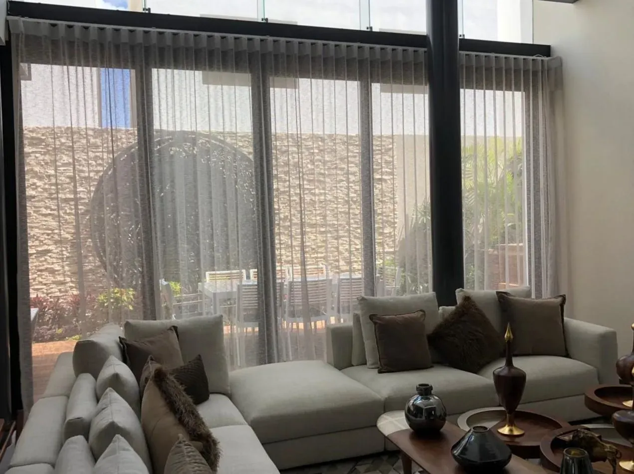 Cortinas sheer de piso a techo frente a ventanales y un sofá