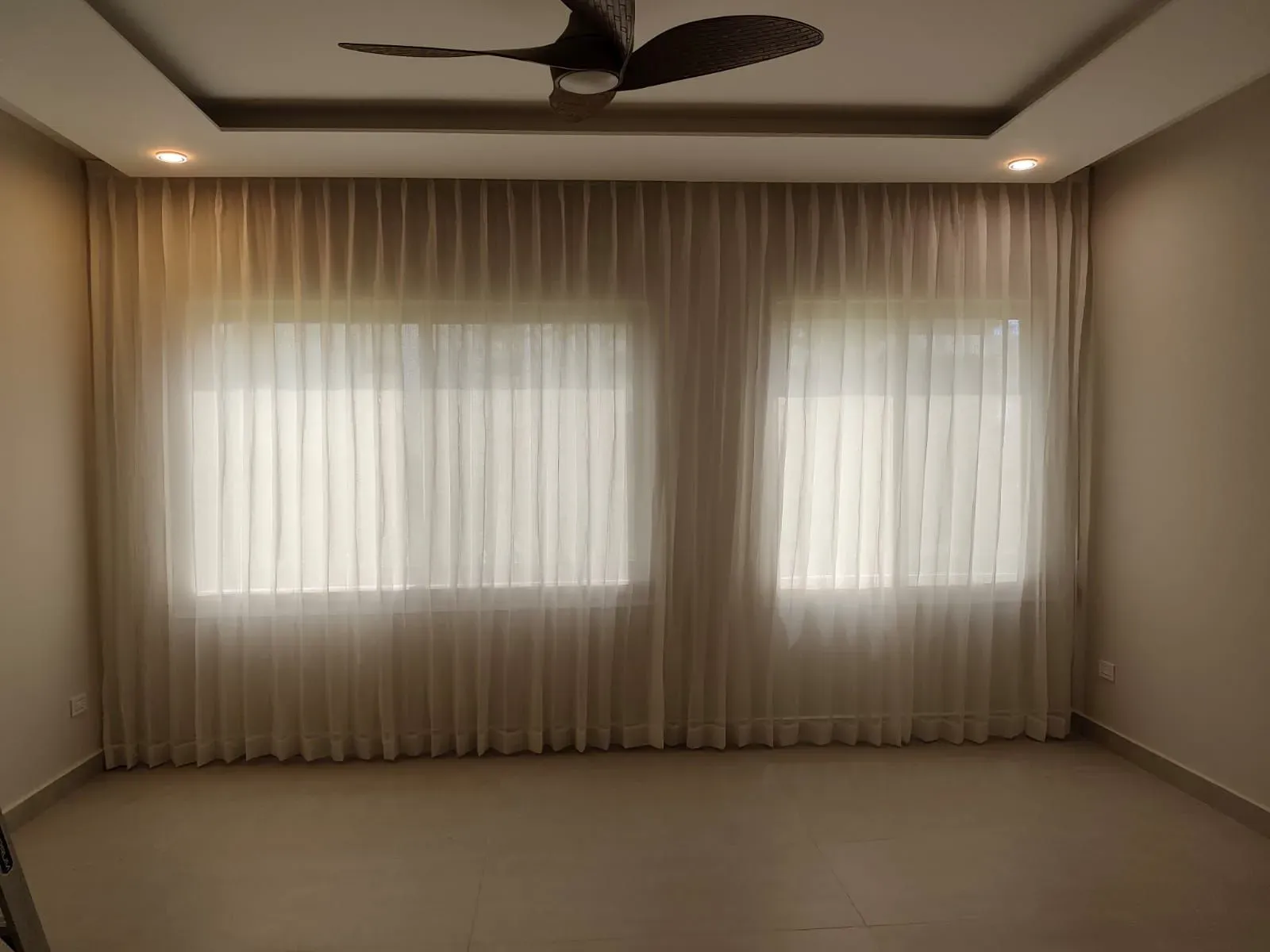 Cortinas sheer de piso a techo frente a dos ventanas en una sala