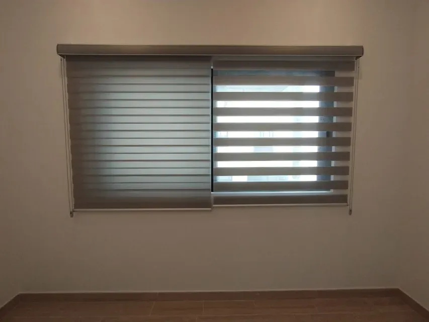 Persiana dual de franjas translúcidas y opacas en una ventana